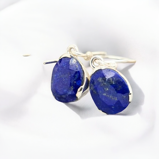 Lapis Lazuli earrings are designed with an uneven wave of sterling silver around the gem in a drop setting, creating an asymmetrical trendy and eye-catching look