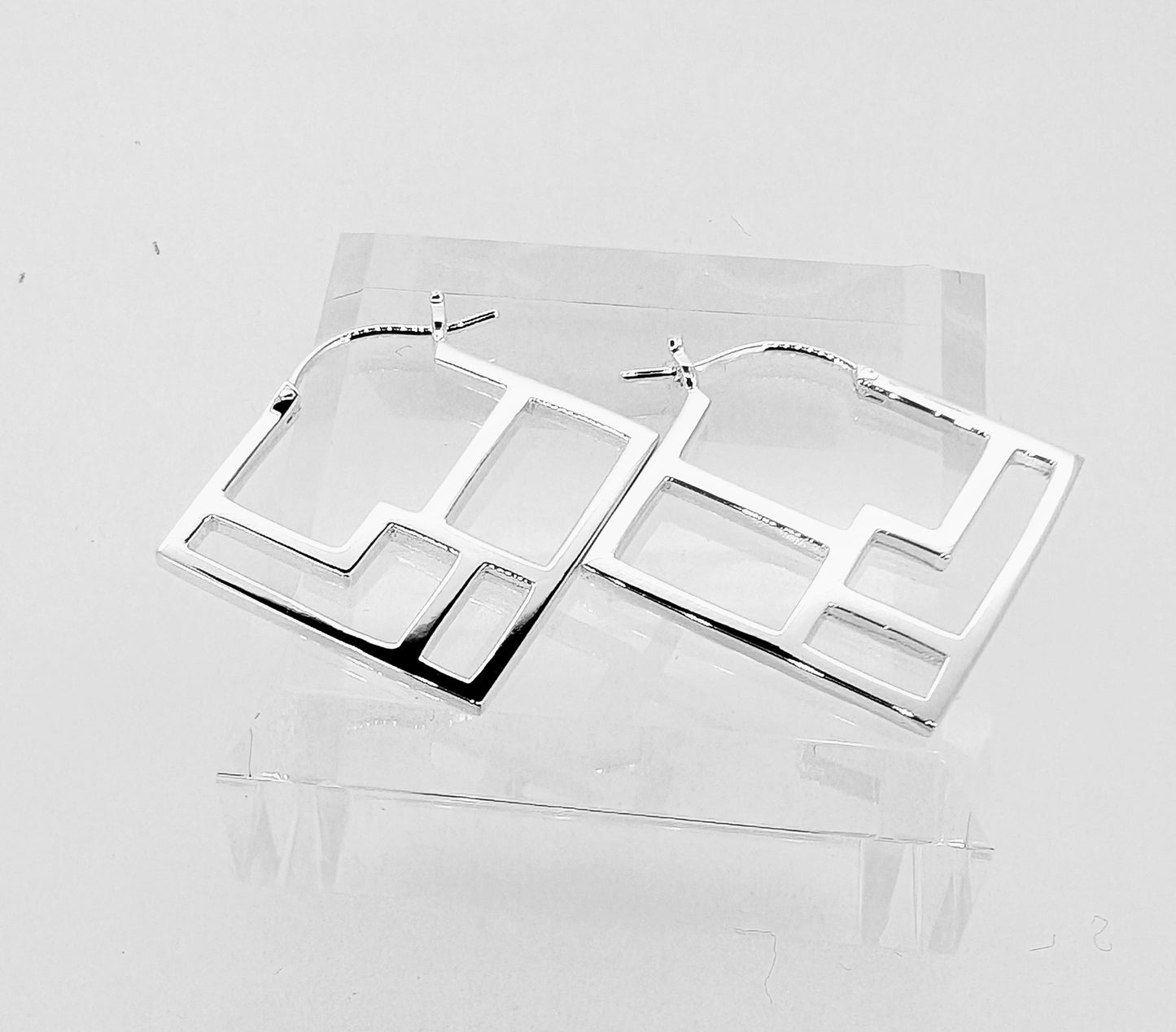 Square sterling silver earrings with a symmetrical web of lines creating an intricate design